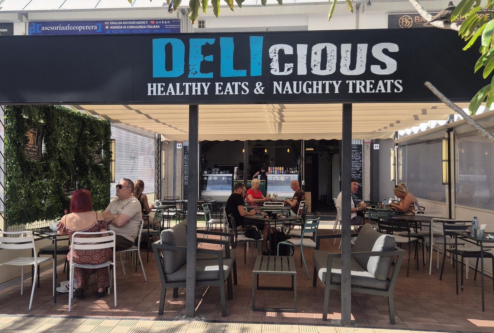 The Delicious storefront on CC Apolo, Los Cristianos — terrace seating under the DELIcious sign